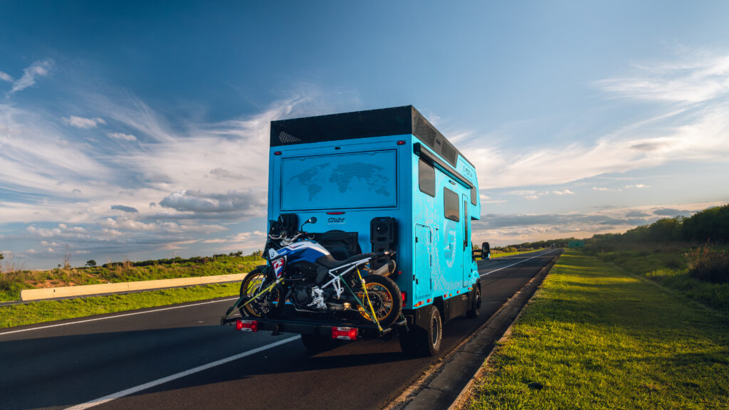 Traseira do motorhome 4x4 Globe Africa com moto no suporte, em uma rodovia