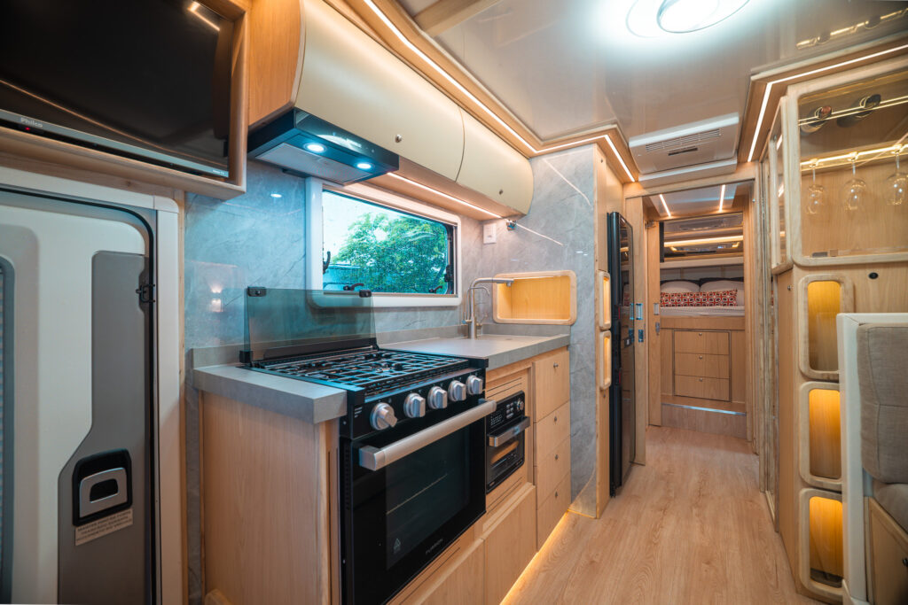 Interior de um motorhome Globe: cozinha com fogão e forno, corredor e móveis em madeira clara